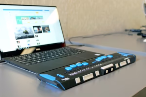 Ordinateur portable affichant un site web, accompagné d’un afficheur braille pour faciliter l’accessibilité numérique